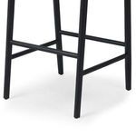 Detail of the lower frame and tapered black oak legs with footrest bars on the Buxton Drifted Oak Bar Stool