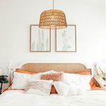 Pendant light styled over bed with neutral bedding and cactus art, highlighting coastal decor vibe