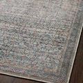 Diagonal close-up of rug on dark flooring emphasizing subtle faded tones and vintage floral motifs
