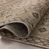 Folded edge of woven charcoal rug highlighting thickness and flexible polyester weave