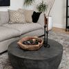 Styled living room setting with the coffee table on a rug, decorated with wooden bowl and candles.