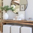 Console table styled with a large round mirror and three patterned ottomans underneath