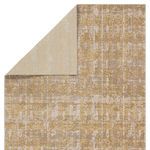 Rug corner lifted to show reverse side with lighter gold and cream pattern