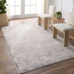 Silver and slate floral rug styled in bright room with wood floor and two white textured chairs