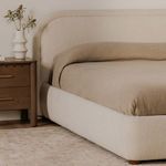 Colin bed corner in cozy room with beige blanket and wooden nightstand against wooden floor