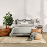 Tustin rug styled in a bedroom setting beneath a bed, highlighting natural colors and soft tones.