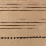 Close-up overhead view focusing on tightly woven brown stripes and symbols across tan background