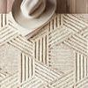 Close-up of Ehren rug's textured wool pile and geometric patterns with a beige hat resting on corner