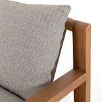Close-up focusing on plush ash-colored cushion fabric texture and wooden chair arm corner