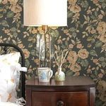 Wallpaper applied on bedroom wall with dark wood nightstand, table lamp, and floral bedding accents