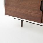 Close-up on metal leg and white lacquer base beneath walnut cabinet door