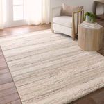 Rug placed in bright room with wooden floor, beside wooden side table and beige armchair