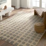 Modern room setting with Japera gray and ivory rug on wooden floor beside a tan leather chair and woven pouf