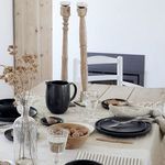 Seed grey stoneware pitcher on a rustic table setting with wooden candlesticks and black dishware