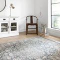 Teagan Denim Mist Rug laid open in bright room with wood chair and white cabinet