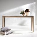 Styled image of the console table in bright room with decorative vases on top and pillows stacked beside
