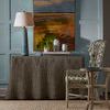 Side view of Gwyneth Wing Chair styled next to gray pleated skirted console and blue paneled wall
