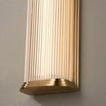 Close-up of aged brass base and ribbed glass detailing on lower part of sconce