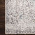 Close-up on Loren Silver Slate Rug's corner displaying tight stitched border and distressed floral detail