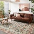 Zion Ivory / Multi Rug styled in modern living room with leather sofa, rattan chair, and minimalistic décor