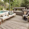 Rug styled in outdoor patio setting under pergola with sofa and fireplace