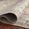 close-up of rug folded to display front pattern and detailed stitched edge on hardwood floor