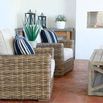 Pair of Havana Club Chairs with beige cushions set outdoors on tile patio with wood coffee table and decorative plants