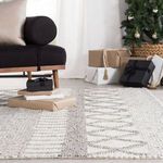 Rug with geometric patterns in neutral nursery with white crib and framed animal prints