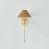 Perilla Wall Sconce shown mounted on light gray wall, full view including long vertical rod and wicker shade