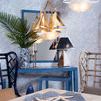 Rear corner view of Gwyneth Wing Chair in nautical-themed room with blue furniture and sailboat light fixtures