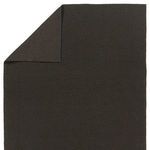 Rug flipped corner showing reverse dark brown and black woven side