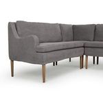 Angled close-up emphasizing curved seat cushion and slender wood legs in gray upholstery