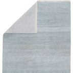 Adler tribal rug folded at corner, showing solid light blue back side