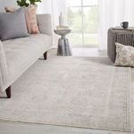 Rug styled in a bright living room beneath gray sofa and decorative pillows