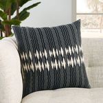 Pillow styled on beige textured sofa with natural light and plants in background