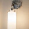 Lighting fixture illuminated showing glow of frosted glass shade on neutral wall