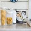 Bianca canisters filled with pasta styled on kitchen counter with cookbook blurred in background