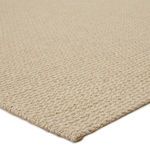 Close-up angled view showing thick woven texture and edge detail of beige rug