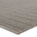 Close-up of tightly braided polypropylene fibers showing texture and edge binding of gray rug