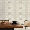 Wallpaper applied on wall in dining area with mid-century style wooden table and rattan chairs, showing scale and room con...