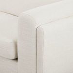 Close-up of rounded armrest with white textured upholstery and seam detail