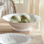 Styled bowl on wooden table holding three green decorative ceramic spheres in a bright room