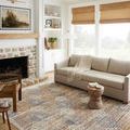 Traditional ivory and multi rug styled in bright living room with sofa, fireplace, and natural light