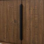 Close-up of black gunmetal-finished iron handle attached to rustic pine cabinet doors.