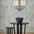 Room context with vase centered on table beneath chandelier and artistic wall