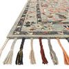 Close-up of rug corner highlighting colorful braided wool tassels and texture of looped wool pile