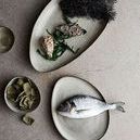 Mame Dip Bowl placed among other natural ceramic serveware pieces with seaweed and fish styling