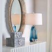 Side view of Lucius Mirror above white cabinet with blue glass lamp and decorative boxes