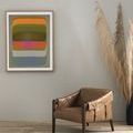 Beige wall setting with framed artwork hung above a modern brown leather armchair and tall, wispy pampas grass