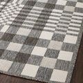 Angled close-up of rug edge and pattern variations in pebble and ivory checkerboard on wood floor.
